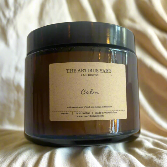 Hand-poured Calm soy wax candle by The Artibus Yard, featuring notes of dark amber, sage, and lavender; crafted in small batches in Warwickshire and poured into a reusable amber glass jar.