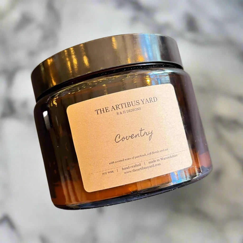 Hand-poured Coventry soy wax candle by The Artibus Yard, featuring notes of patchouli, soft florals and oak; crafted in small batches in Warwickshire and poured into a reusable amber glass jar.