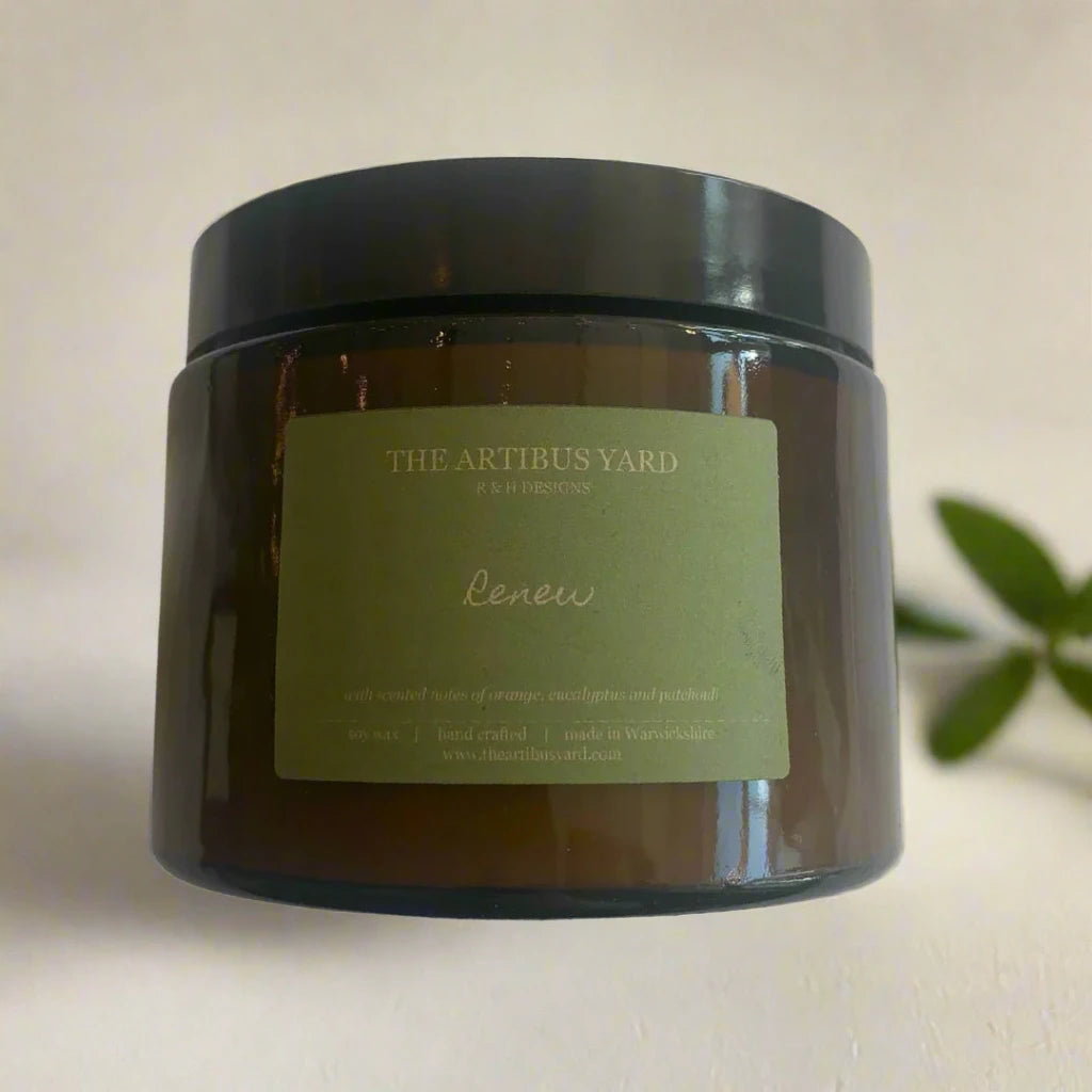 Hand-poured Renew soy wax candle by The Artibus Yard, featuring notes of orange, patchouli and eucalyptus; crafted in small batches in Warwickshire and poured into a reusable amber glass jar.