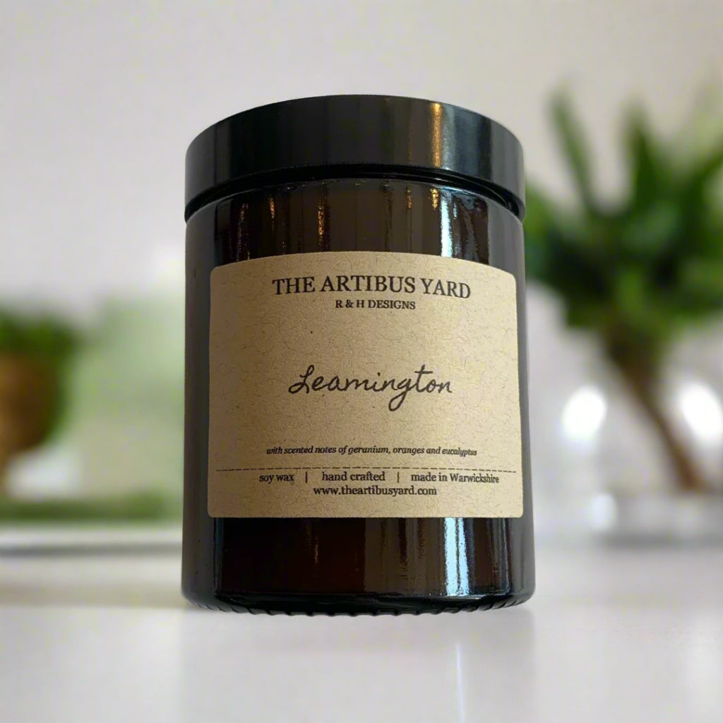 Hand-poured Leamington soy wax candle by The Artibus Yard, featuring notes of orange, geranium and eucalyptus; crafted in small batches in Warwickshire and poured into a reusable amber glass jar.