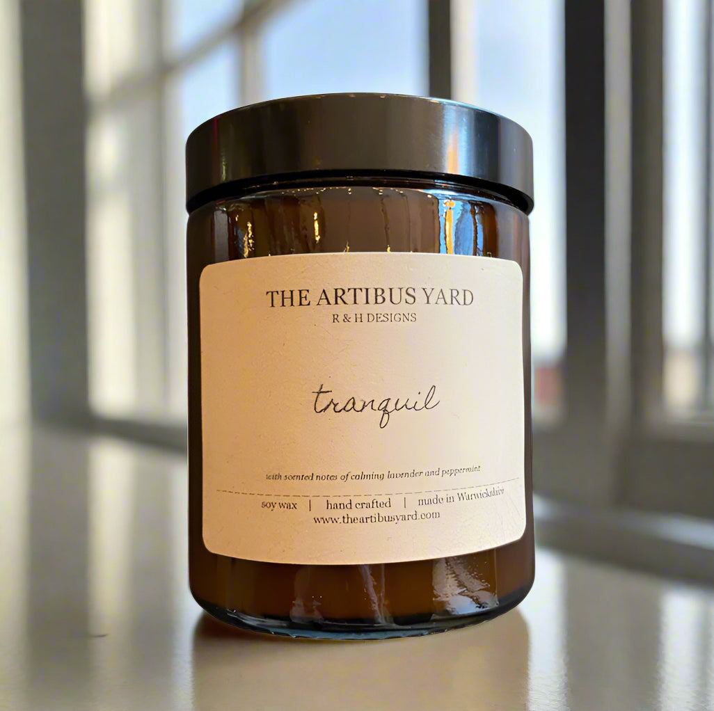 Hand-poured Tranquil soy wax candle by The Artibus Yard, featuring notes of lavender and peppermint; crafted in small batches in Warwickshire and poured into a reusable amber glass jar.
