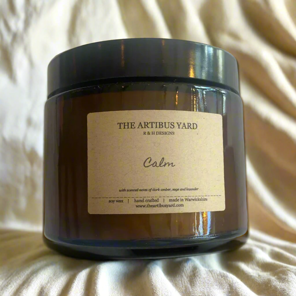 Hand-poured Calm soy wax candle by The Artibus Yard, featuring notes of dark amber, sage, and lavender; crafted in small batches in Warwickshire and poured into a reusable amber glass jar.