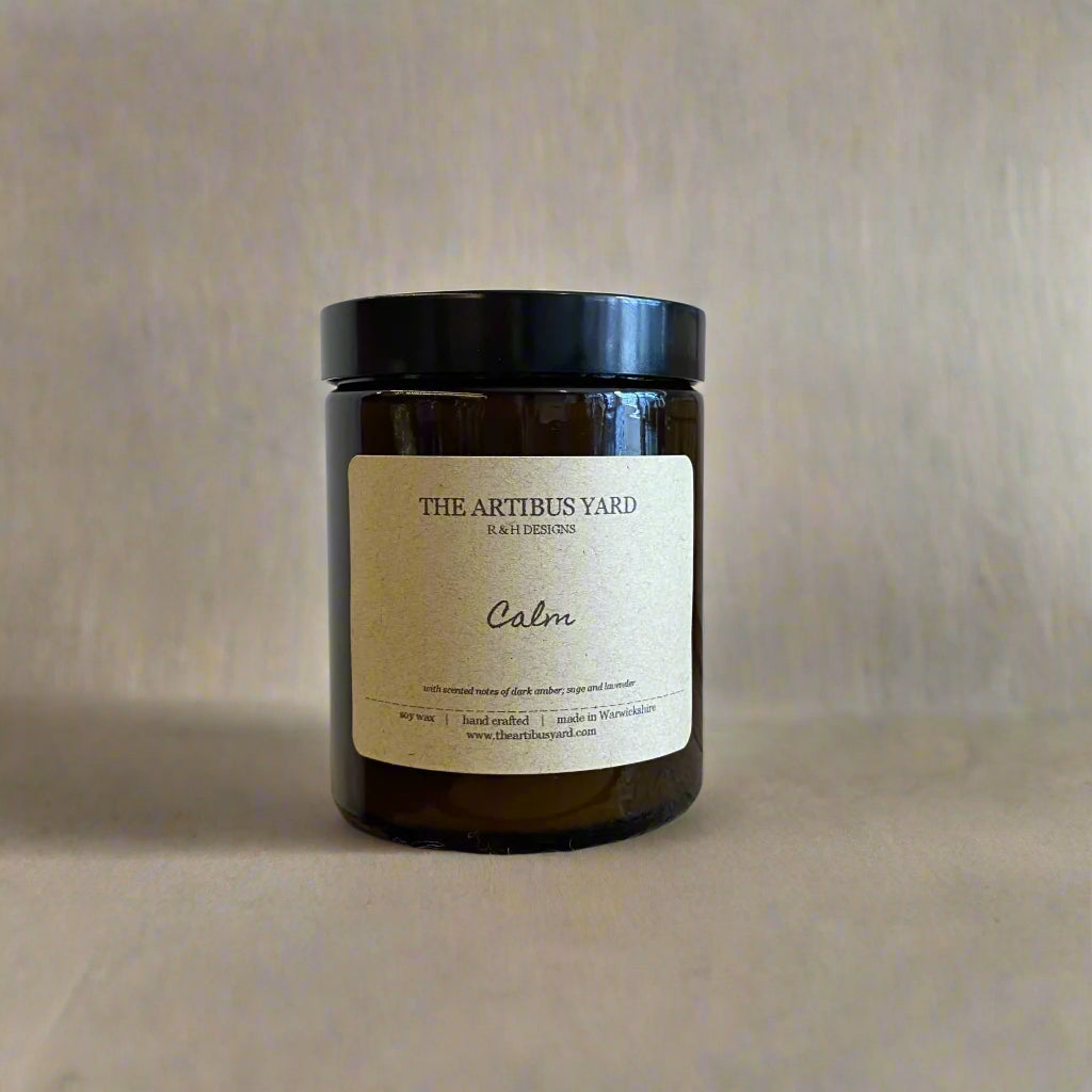 Hand-poured Calm soy wax candle by The Artibus Yard, featuring notes of dark amber, sage, and lavender; crafted in small batches in Warwickshire and poured into a reusable amber glass jar.