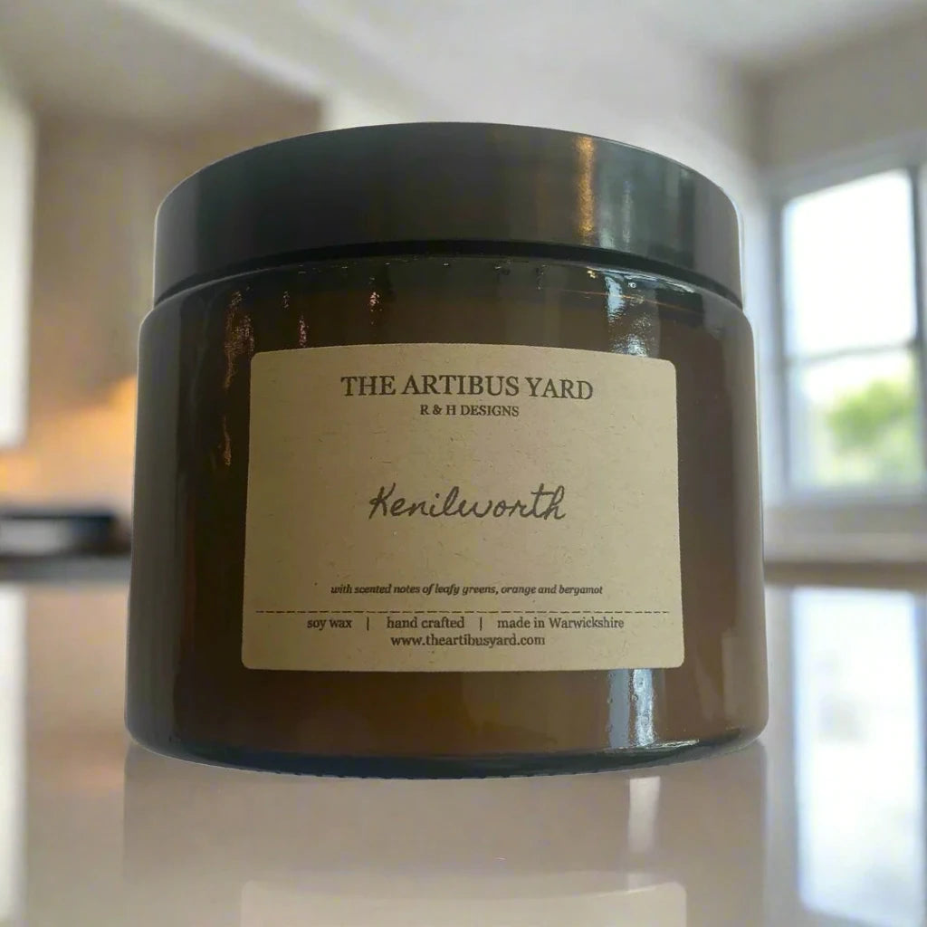 Hand-poured Kenilworth soy wax candle by The Artibus Yard, featuring notes of leafy greens, orange, and bergamot; crafted in small batches in Warwickshire and poured into a reusable amber glass jar.