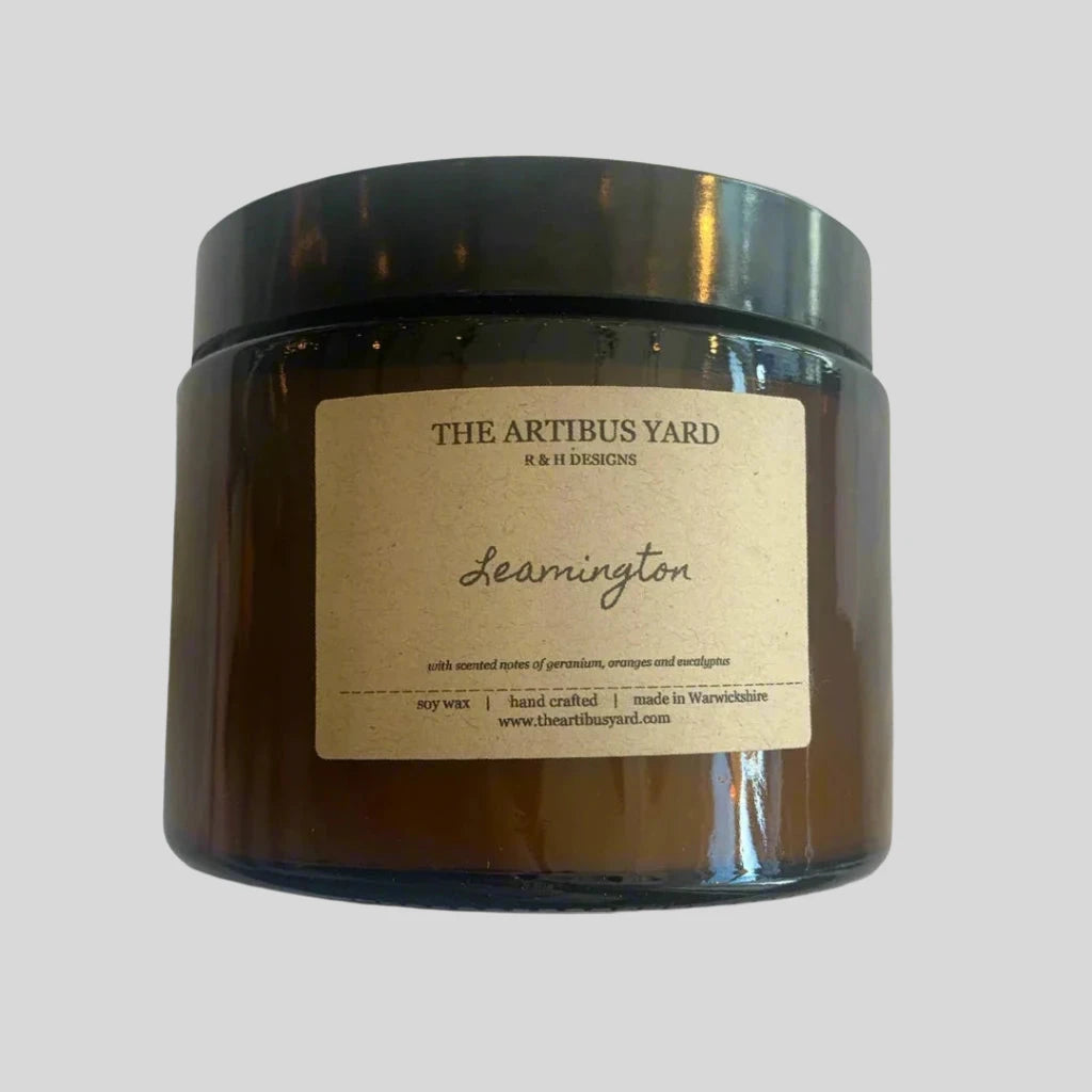 Hand-poured Leamington soy wax candle by The Artibus Yard, featuring notes of orange, geranium and eucalyptus; crafted in small batches in Warwickshire and poured into a reusable amber glass jar.