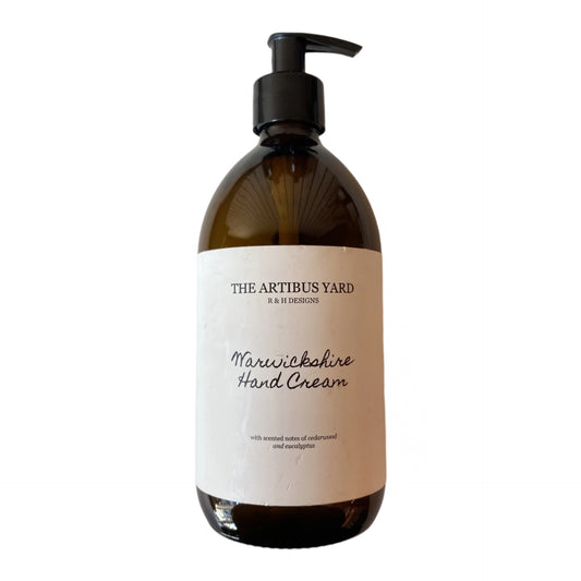 Warwickshire scented hand cream by The Artibus Yard, enriched with nourishing ingredients and fresh and woody notes, packaged in an amber glass bottle with pump dispenser. 