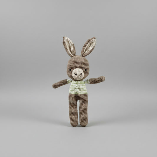 Hand holding a crocheted rabbit toy against a plain background