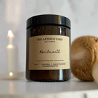 Hand-poured Kenilworth soy wax candle by The Artibus Yard, featuring notes of leafy greens, orange, and bergamot; crafted in small batches in Warwickshire and poured into a reusable amber glass jar.