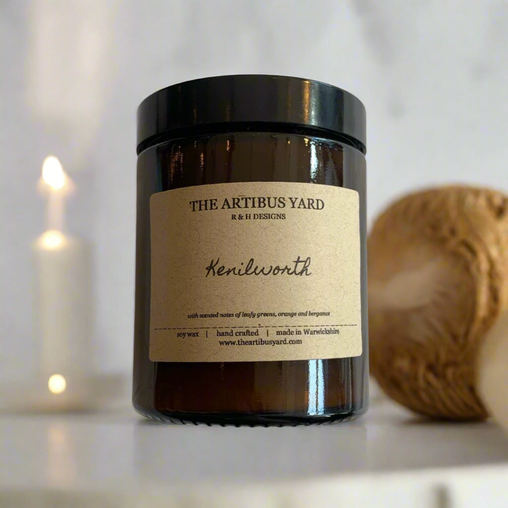 Hand-poured Kenilworth soy wax candle by The Artibus Yard, featuring notes of leafy greens, orange, and bergamot; crafted in small batches in Warwickshire and poured into a reusable amber glass jar.